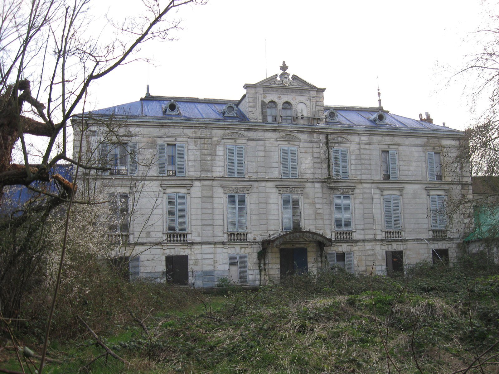 Façade néo-classique du château Lot à Ris-Orangis, volets fermés et toiture bâchée